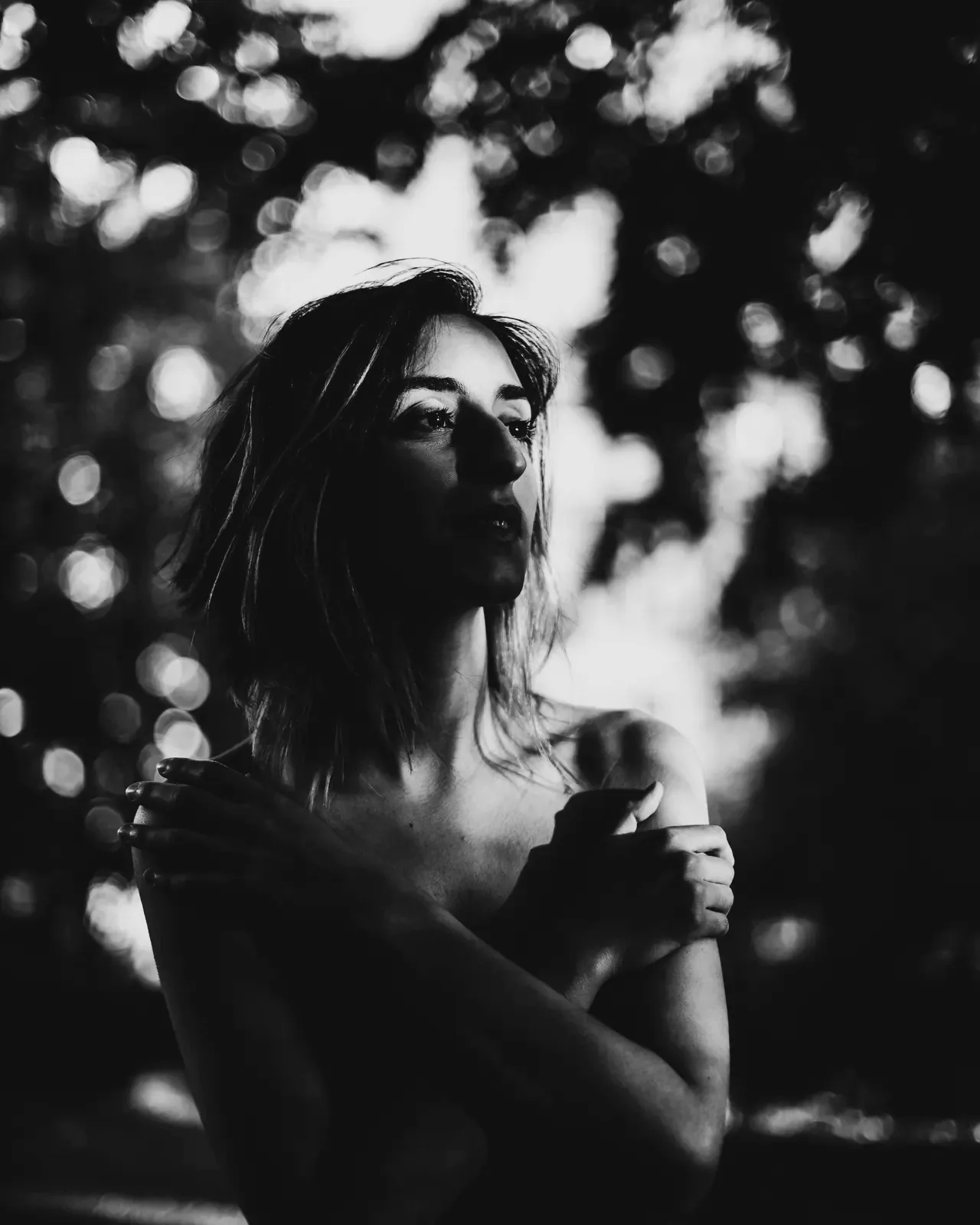 Luna Škopelja — black-and-white portrait among trees, arms crossed