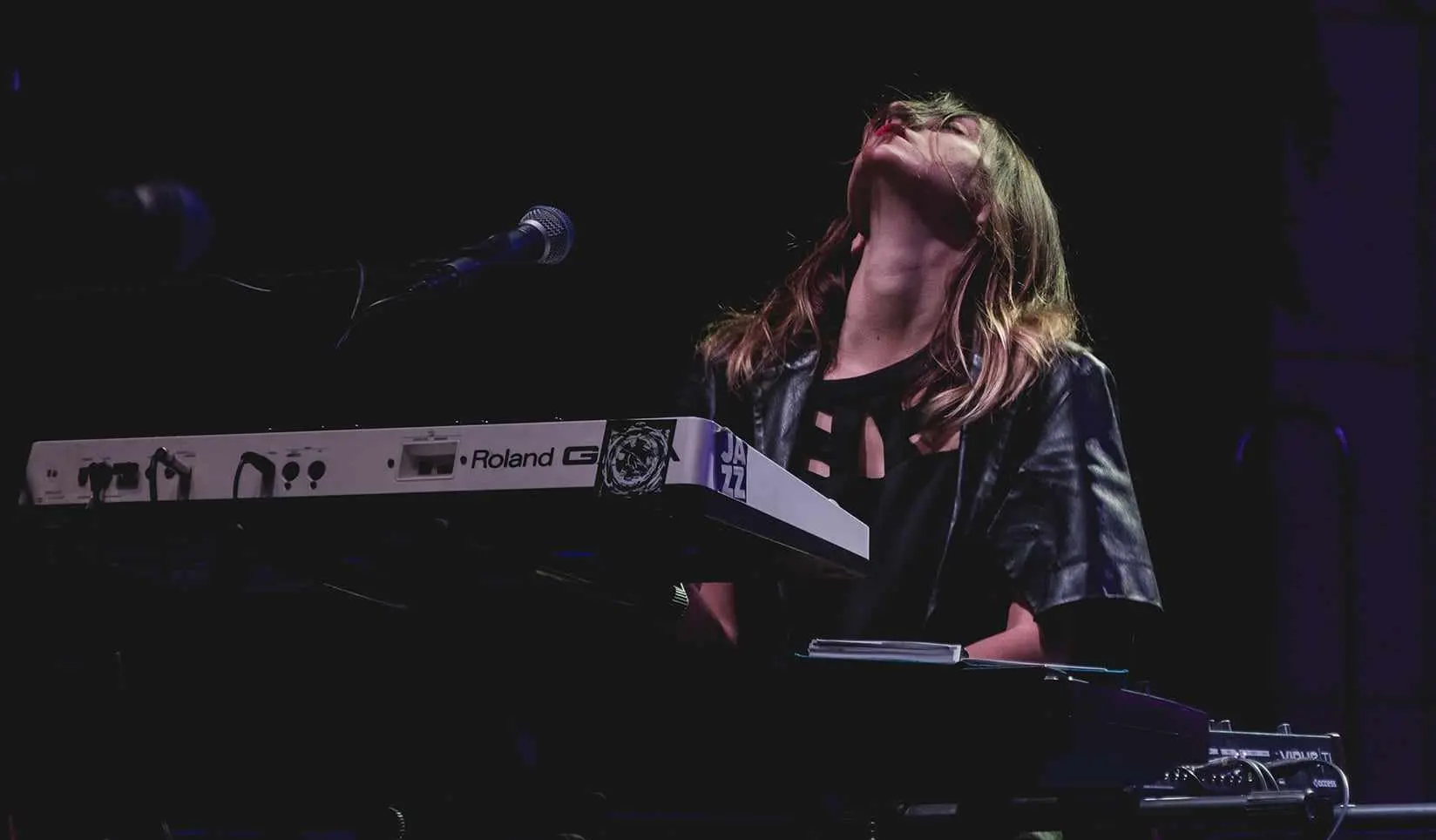 Luna Škopelja performing live at her keyboard, head thrown back under stage light